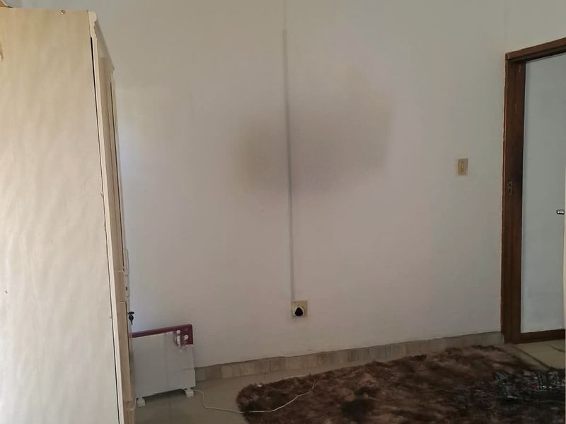 A bedroom featuring tiled flooring and visible wall staining, requiring cosmetic updates to improve the overall aesthetic and condition.