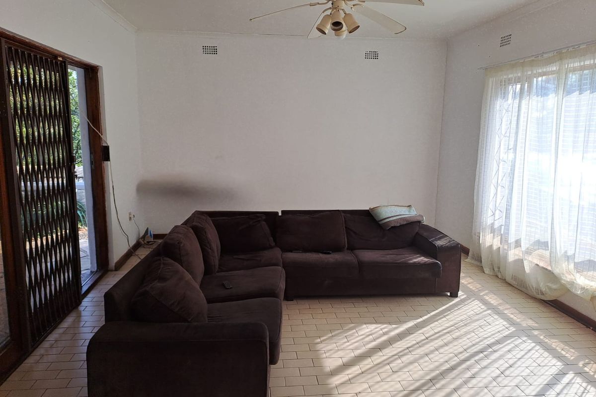 A living room featuring tiled flooring, a ceiling fan, and access to an outdoor area through a security gate.
