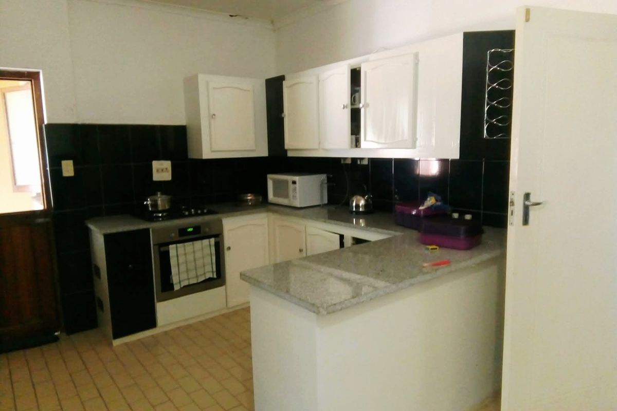 A functional kitchen featuring white cabinetry, granite countertops, a built-in oven, and a tiled backsplash, offering a practical layout for daily meal preparation.