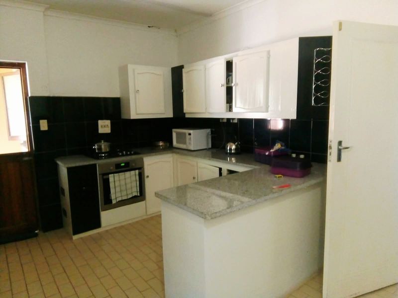 A functional kitchen featuring white cabinetry, granite countertops, a built-in oven, and a tiled backsplash, offering a practical layout for daily meal preparation.