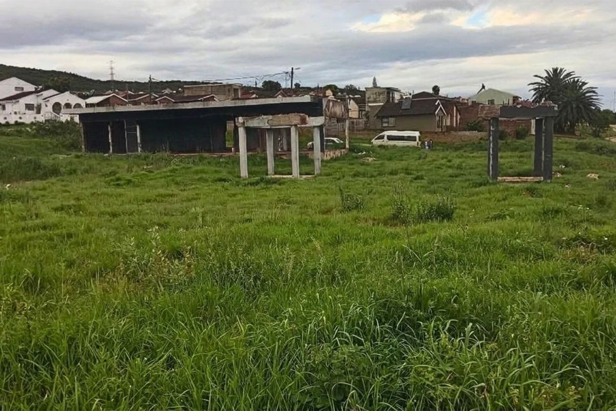 Vacant residential land featuring an incomplete concrete structure and foundation, situated in an established neighborhood setting.