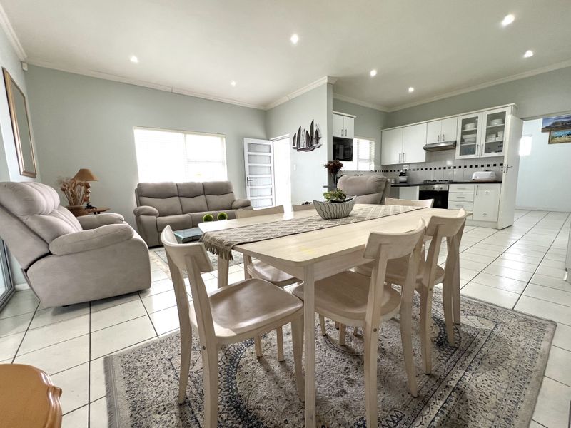Spacious open-plan living, dining, and kitchen area featuring tiled floors, recessed lighting, and a functional kitchen with built-in cabinetry and appliances.