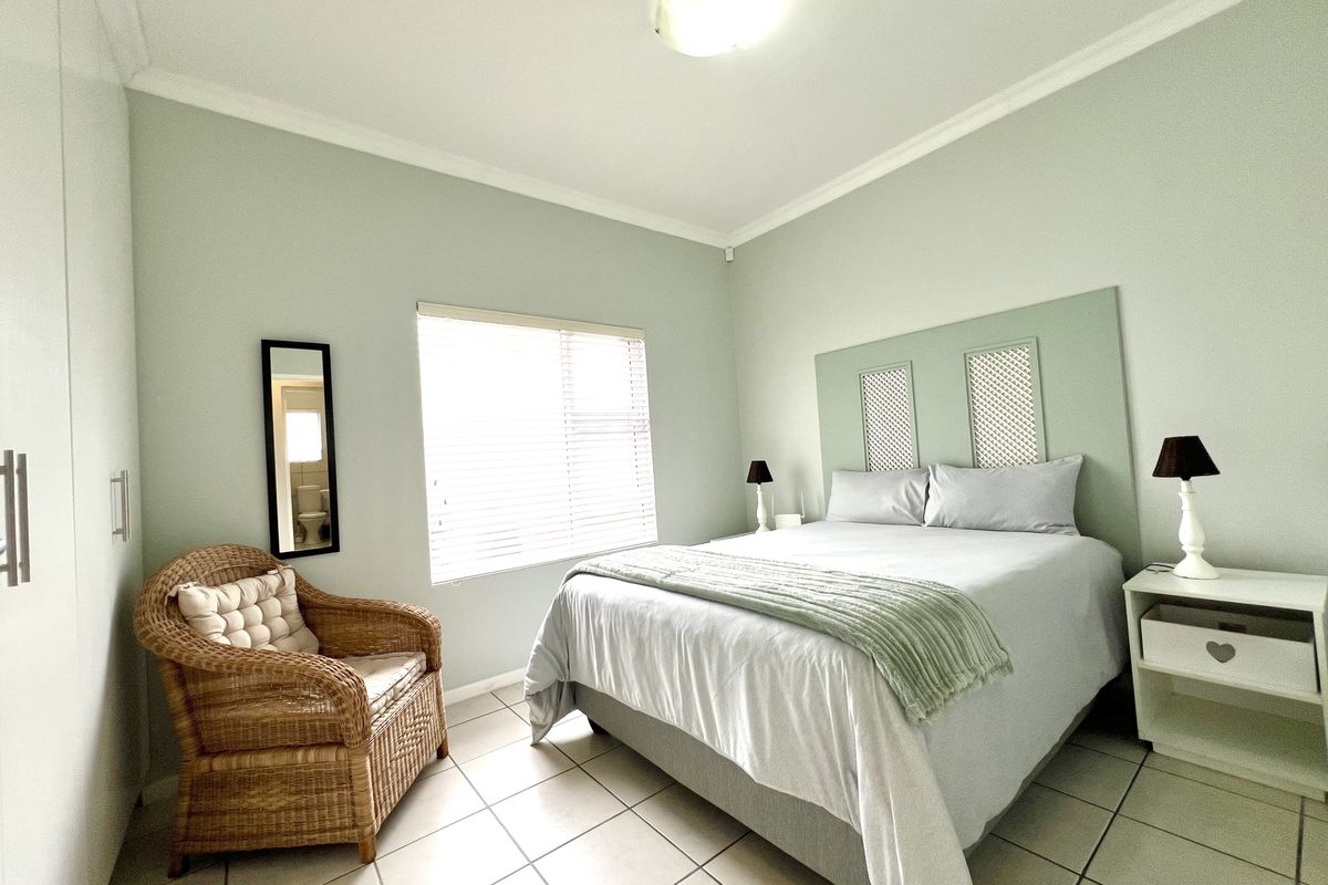 A well-maintained bedroom featuring tiled flooring, built-in cupboards, and a neutral color palette with natural light from the window.
