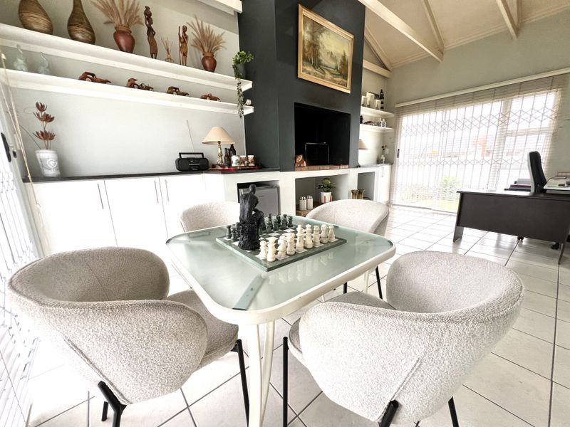 Spacious living area featuring a built-in fireplace, vaulted ceilings, and custom cabinetry, offering a bright and functional space with tiled flooring throughout.