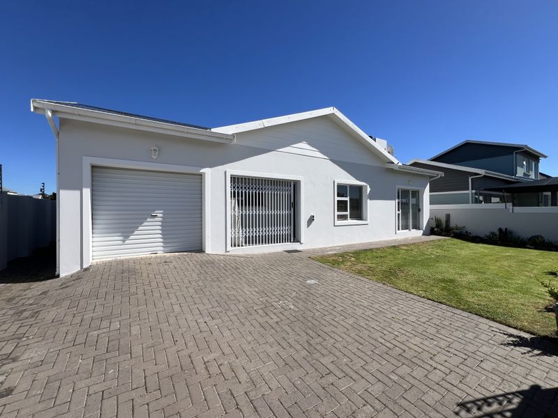 Front view of a well-maintained house featuring a paved driveway, single garage, and a neat front lawn with secure access.
