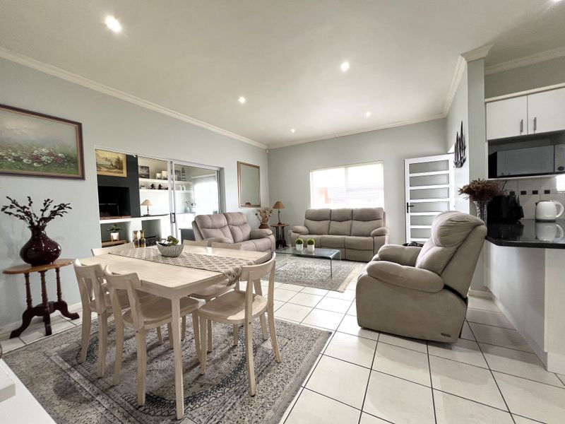 Spacious open-plan living and dining area featuring tiled floors, recessed lighting, and a modern kitchen with granite countertops and ample cabinetry.