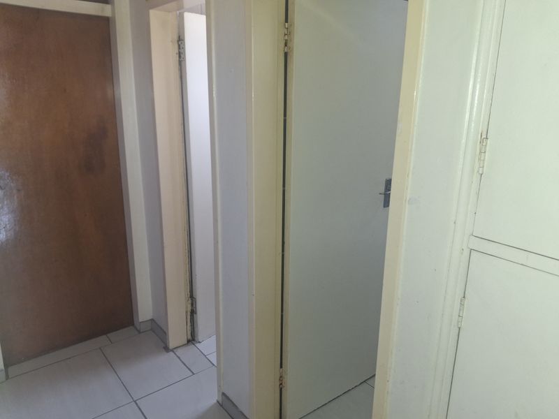 A functional hallway featuring tiled flooring and multiple internal doors, showing signs of wear and requiring cosmetic updates.