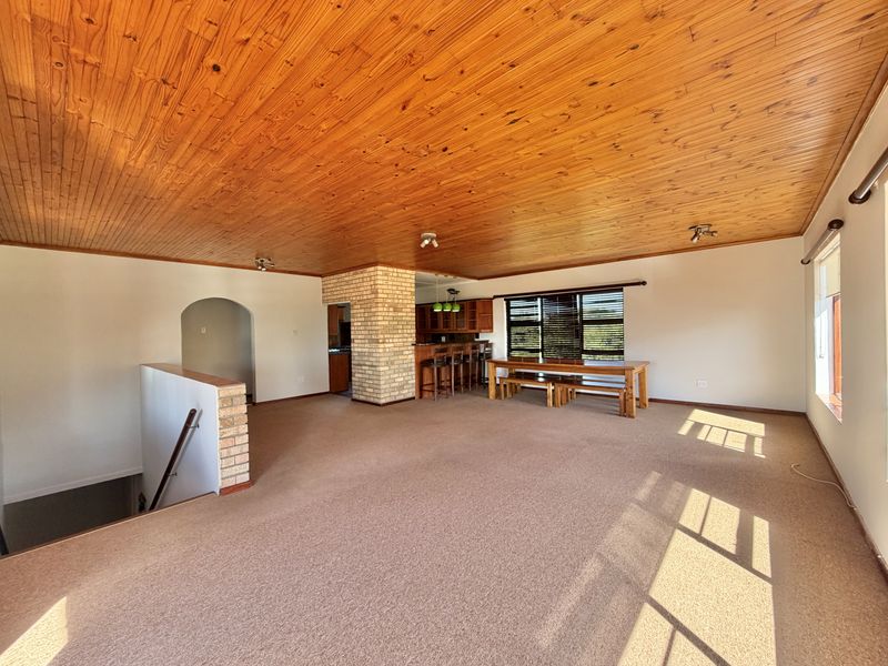 Spacious open-plan living and dining area featuring a distinctive timber tongue and groove ceiling, exposed brick accents, and integrated kitchen breakfast bar.