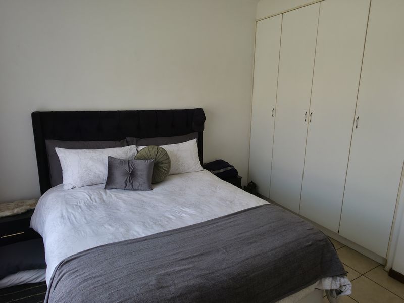 A functional bedroom featuring built-in cupboards and tiled flooring, offering a neutral space ready for personalization.