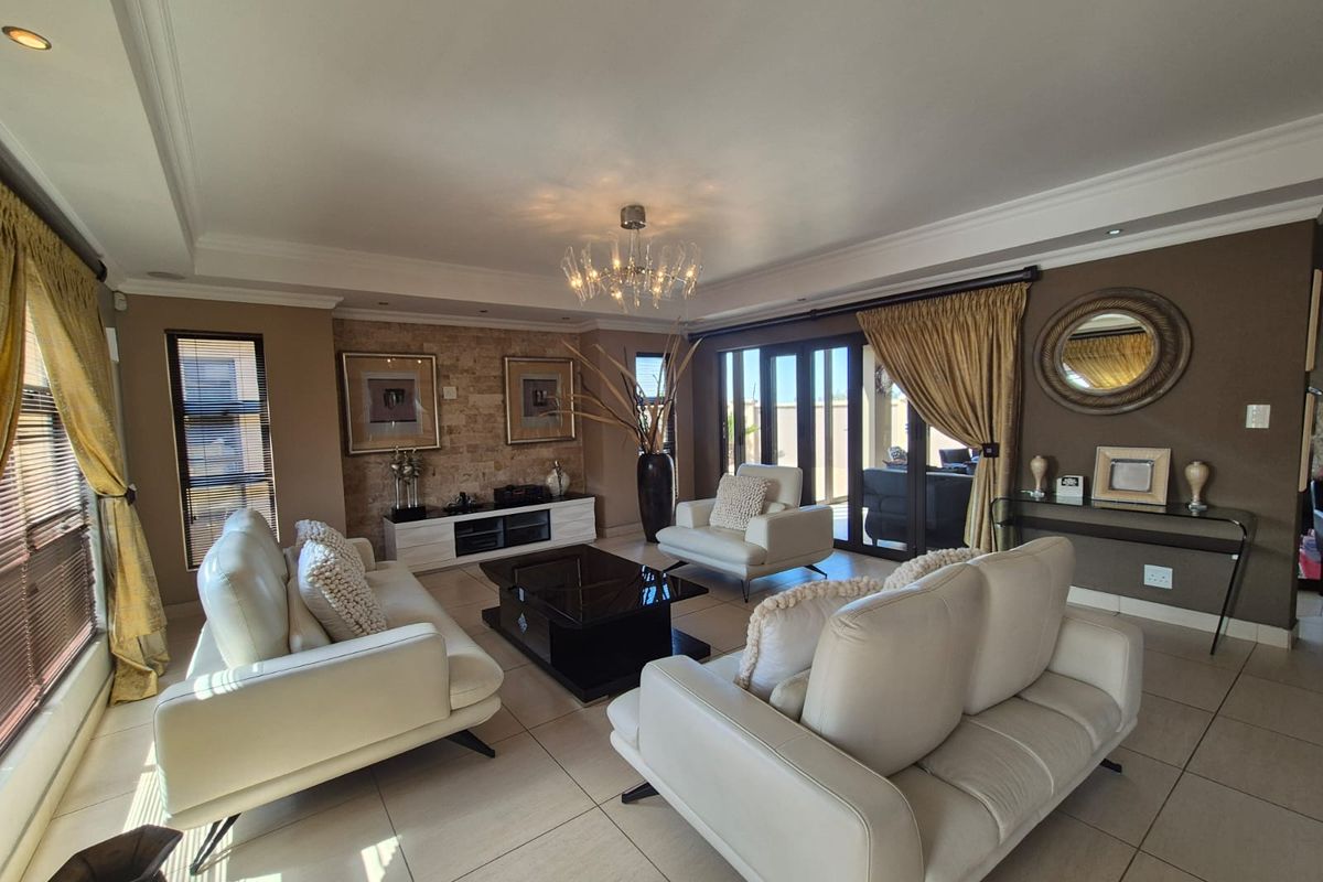 Spacious living room featuring a stone accent wall, tiled flooring, recessed ceiling lighting, and large sliding glass doors leading to the outdoor area.
