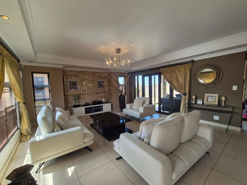 Spacious living room featuring a stone accent wall, tiled flooring, recessed ceiling lighting, and large sliding glass doors leading to the outdoor area.