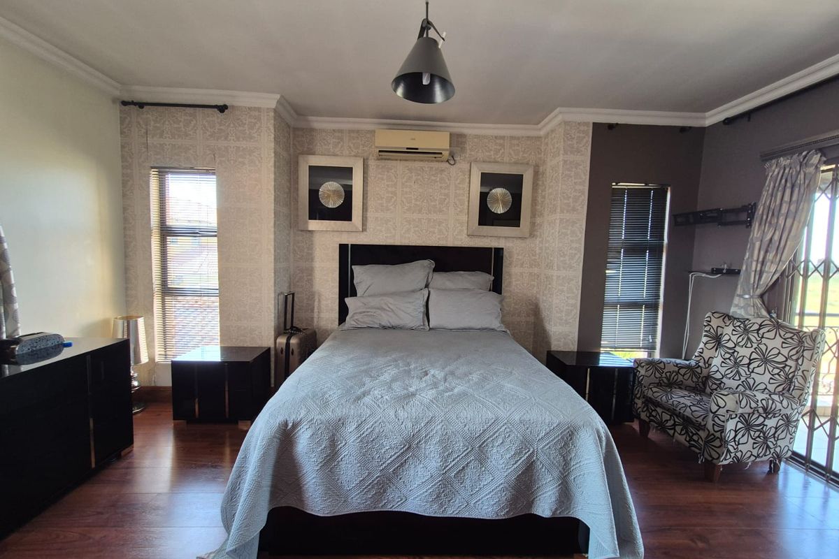 A well-maintained bedroom featuring laminate flooring, split-system air conditioning, and dual windows with venetian blinds, offering a comfortable and functional living space.