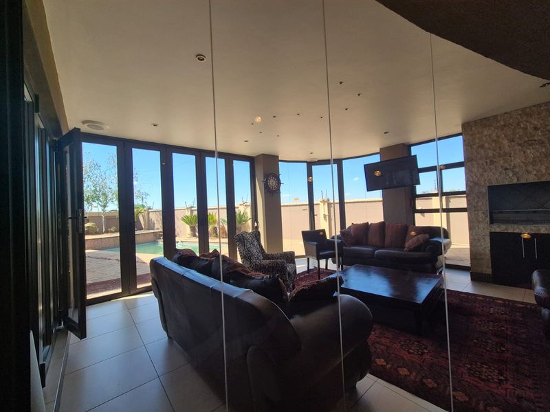 Spacious living room featuring large bi-fold doors opening to the pool area, a stone feature wall with a built-in fireplace, and tiled flooring.