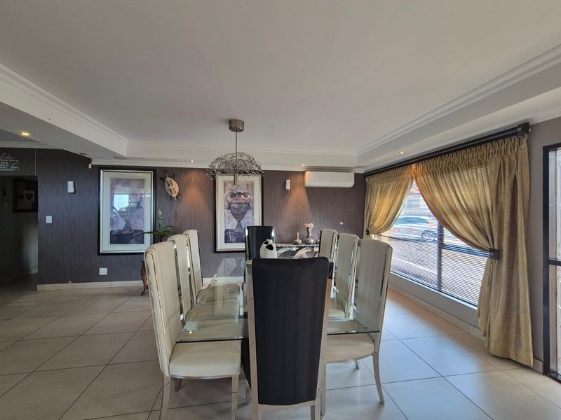 A well-maintained dining room featuring tiled flooring, textured feature walls, recessed lighting, and a wall-mounted air conditioning unit.