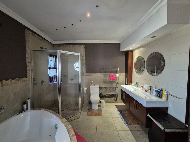Spacious bathroom featuring a corner shower, built-in bathtub, and double vanity. Requires repair to wall tiling and plumbing behind the toilet.