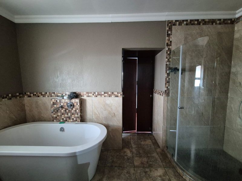 A bathroom featuring a freestanding bathtub, a glass-enclosed shower, and decorative mosaic tile accents with neutral wall finishes.