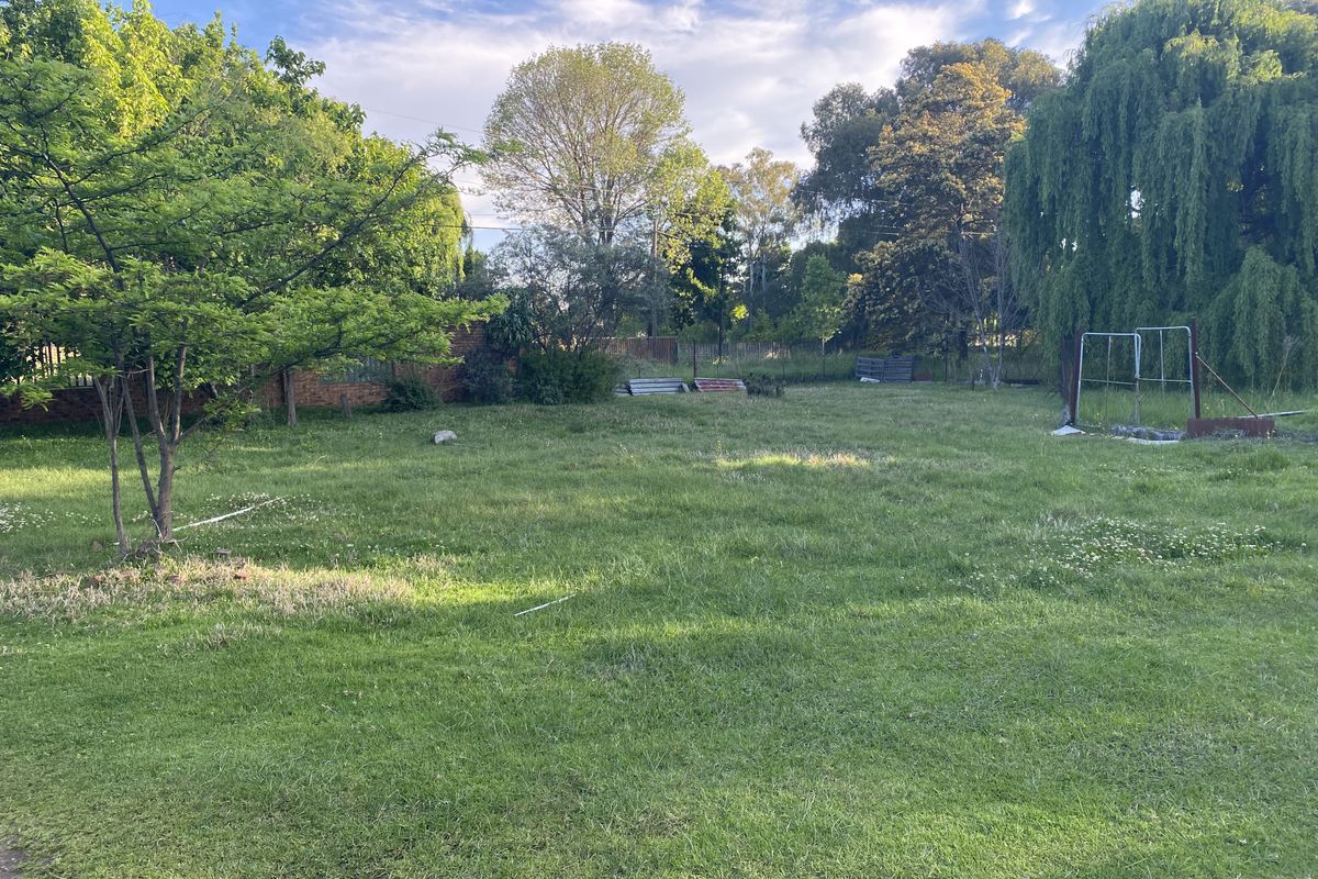 A spacious, level garden area featuring established trees and a brick boundary wall, offering potential for landscaping or outdoor development.