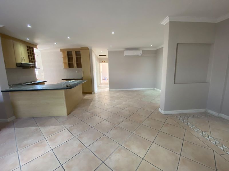 Spacious open-plan living area featuring a kitchen with built-in cabinetry, stone countertops, and tiled flooring throughout.