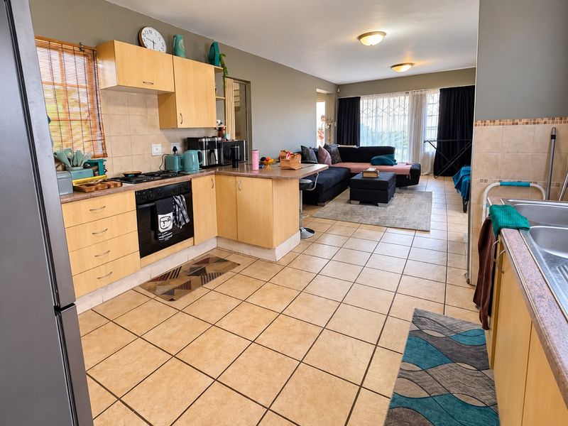 Open-plan kitchen and living area featuring light wood cabinetry, tiled flooring, and direct access to the living space.