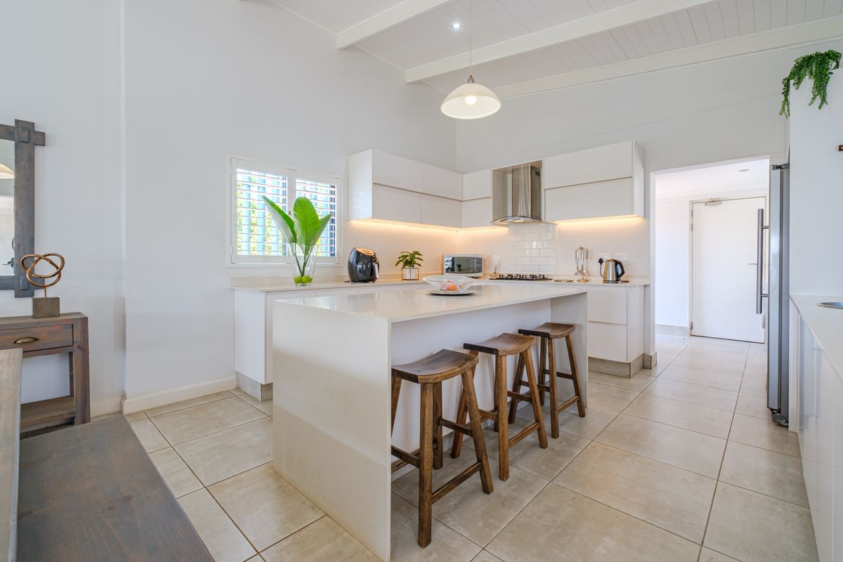 Modern kitchen featuring a central island with quartz countertops, sleek white cabinetry, subway tile backsplash, and high-quality finishes throughout.