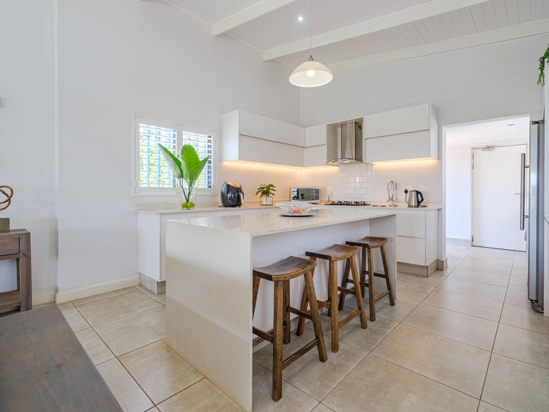 Modern kitchen featuring a central island with quartz countertops, sleek white cabinetry, subway tile backsplash, and high-quality finishes throughout.