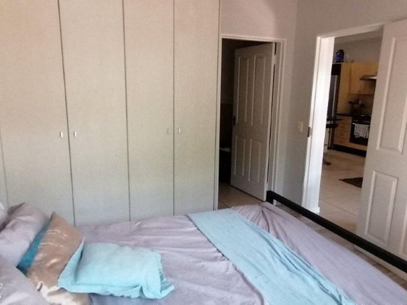 A bedroom featuring built-in cupboards and access to an adjacent room, with neutral finishes and standard panel doors.