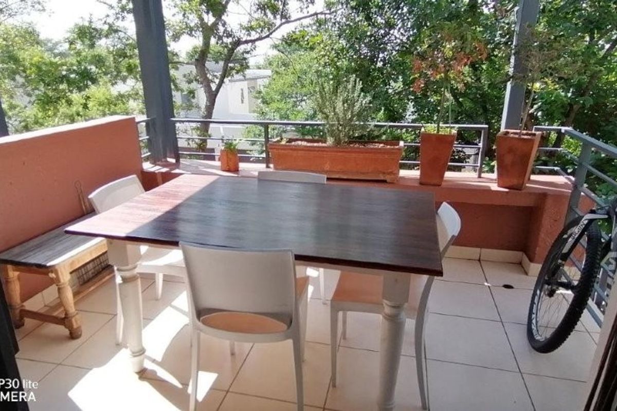 A covered balcony featuring tiled flooring, a metal safety railing, and a built-in planter box, offering an outdoor space for relaxation.