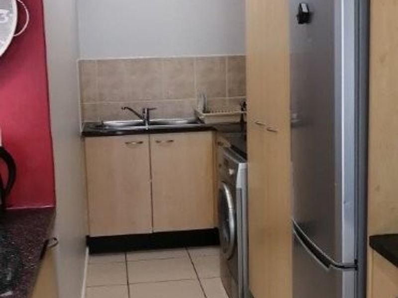 A functional scullery area featuring built-in cabinetry, a stainless steel sink, tiled splashback, and tiled flooring, providing efficient utility space.