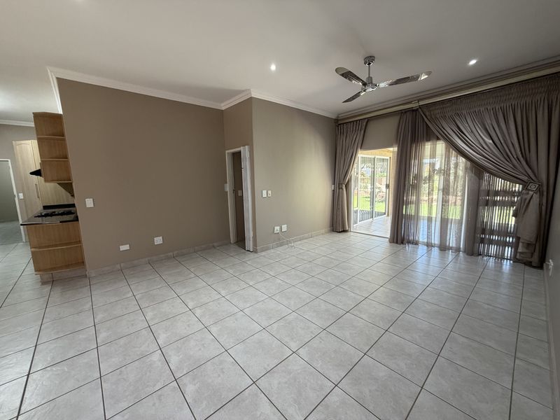 Spacious open-plan living area featuring neutral tiled flooring, recessed lighting, a ceiling fan, and direct access to the outdoor patio through sliding glass doors.