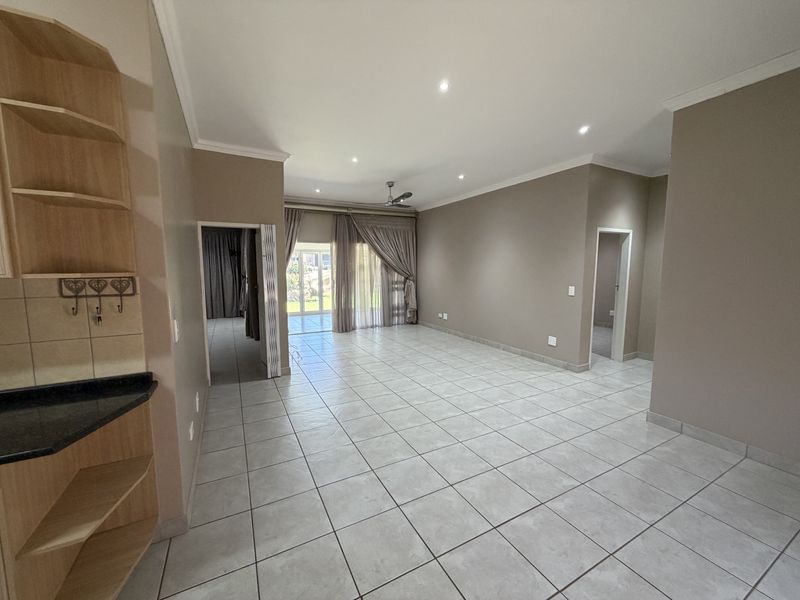 Spacious open-plan living area featuring neutral tiled flooring, recessed lighting, a ceiling fan, and direct access to the outdoor patio through sliding glass doors.