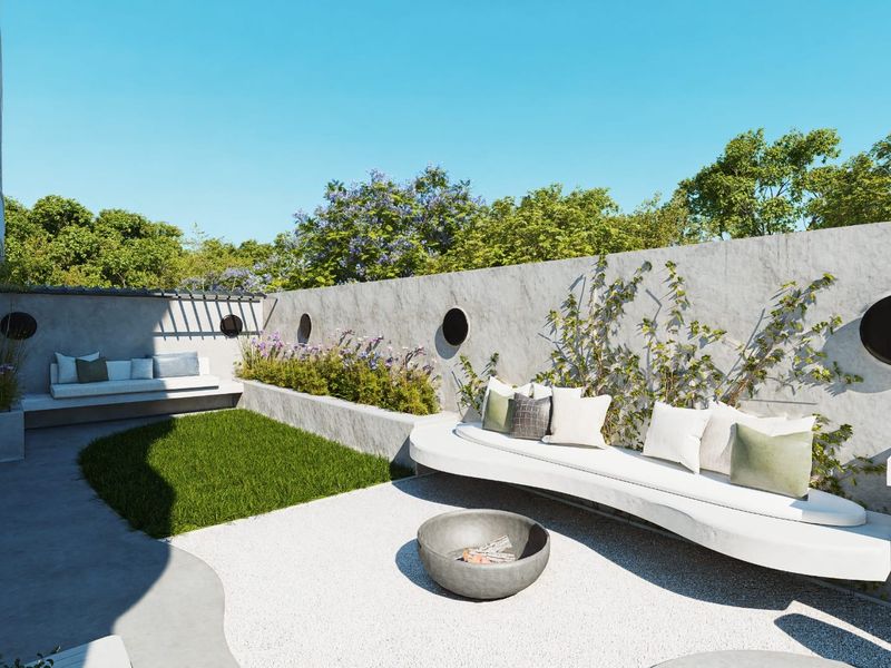 A modern outdoor patio area featuring built-in concrete bench seating, a raised planter box, and a gravel courtyard with a central fire pit.