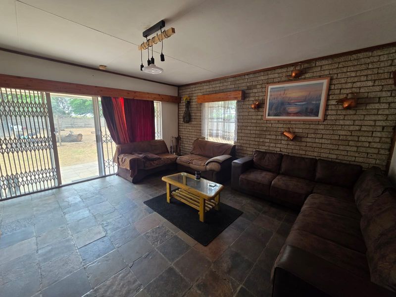 Spacious living room featuring exposed brick walls, slate tile flooring, and large sliding glass doors providing access to the outdoor area.