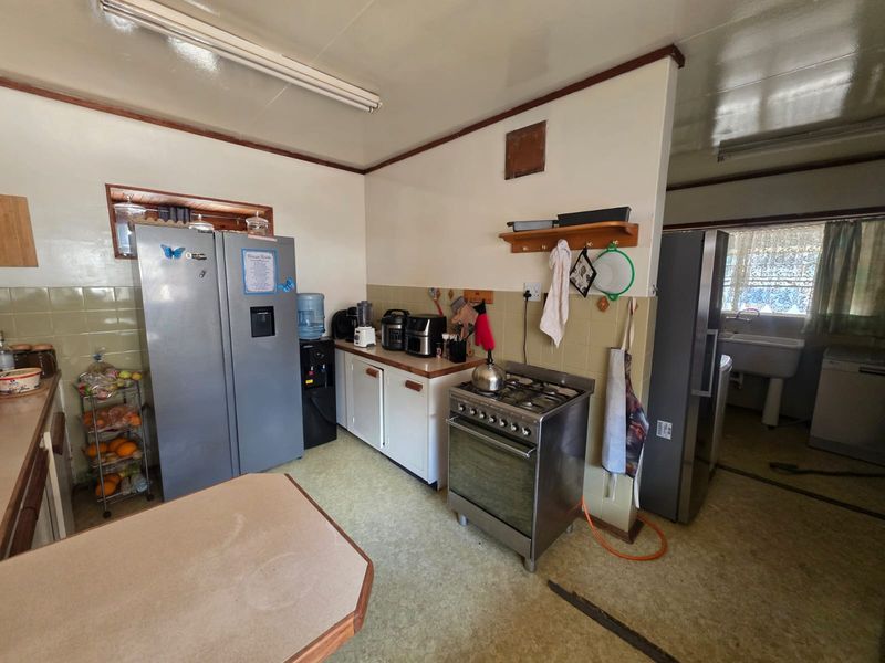 A functional kitchen featuring a gas stove, tiled backsplash, and built-in cabinetry, offering potential for modernization and cosmetic updates.
