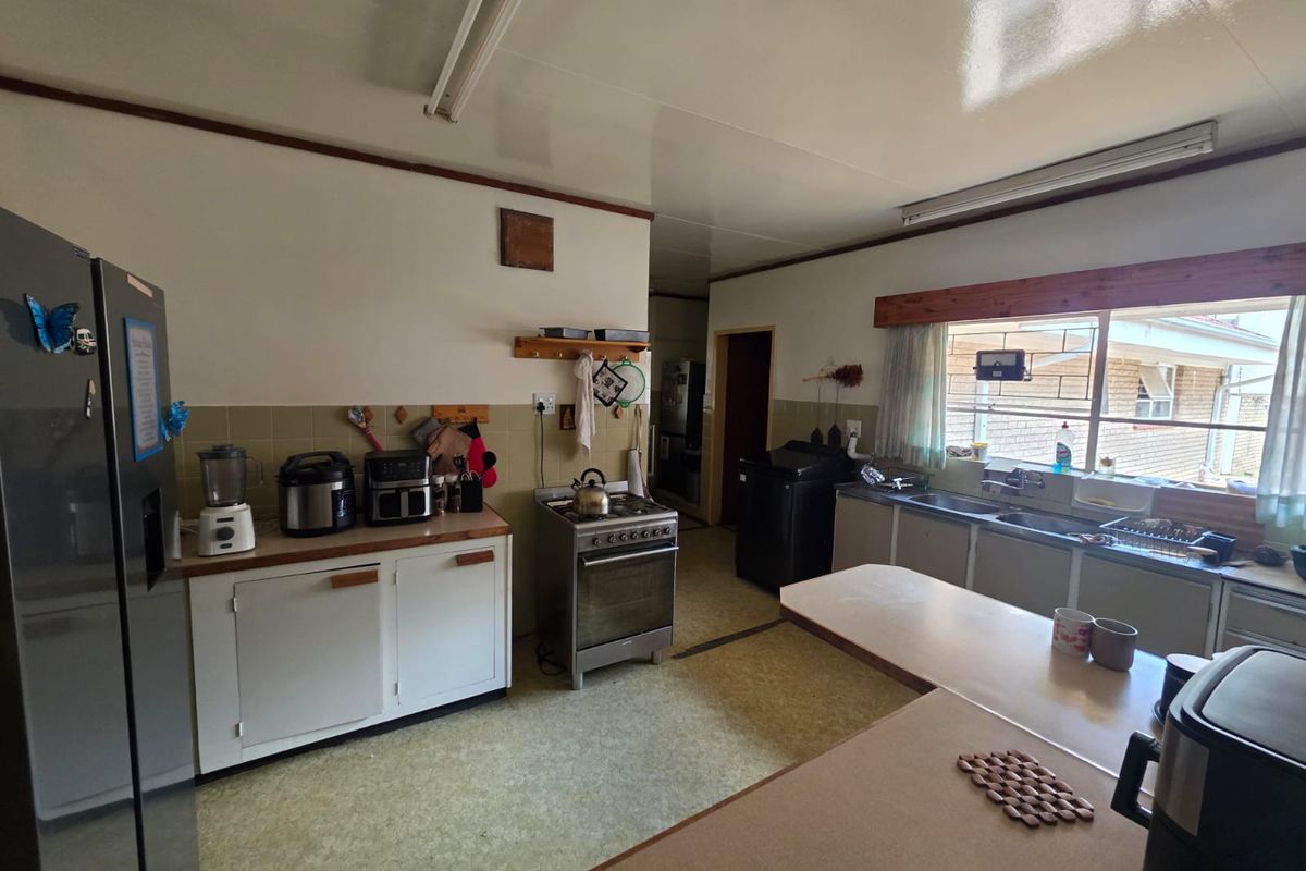 A functional kitchen featuring dated cabinetry, laminate countertops, a double basin sink, and a freestanding stove, offering significant potential for modern renovation.