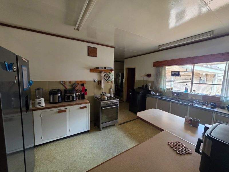 A functional kitchen featuring dated cabinetry, laminate countertops, a double basin sink, and a freestanding stove, offering significant potential for modern renovation.