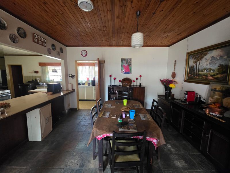 Open-plan dining area featuring timber ceilings, stone tile flooring, and a breakfast bar connecting to the kitchen space.