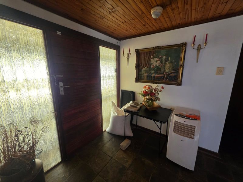 Entrance foyer featuring slate tile flooring, a timber tongue and groove ceiling, and a solid timber front door with textured glass sidelights.