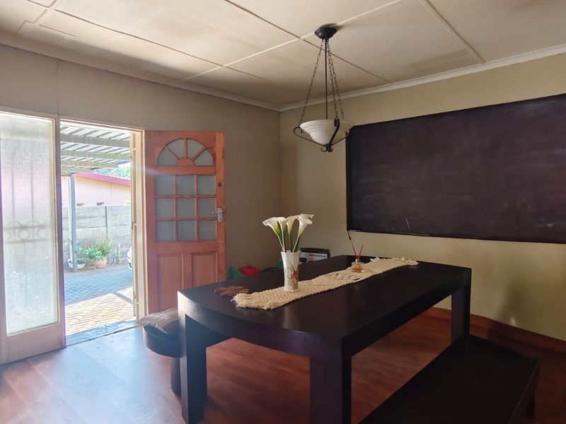 Dining area featuring laminate flooring, pendant lighting, and direct access to the exterior through a timber door.