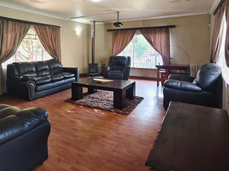 Spacious living room featuring laminate flooring, a wood-burning fireplace, and a ceiling-mounted projector, requiring some ceiling maintenance and cosmetic updates.