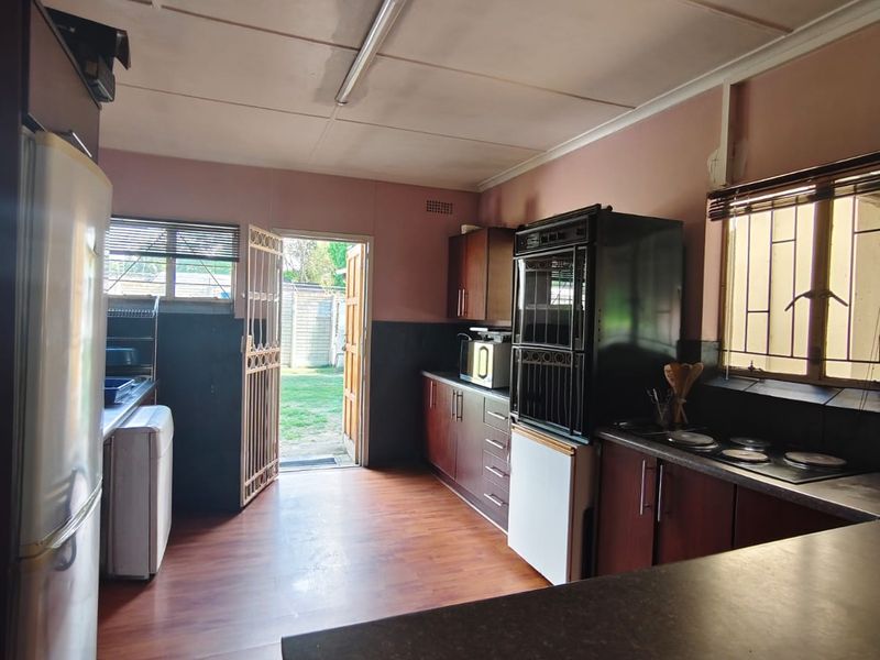 Functional kitchen featuring built-in cabinetry, integrated oven and hob, laminate countertops, and direct access to the rear garden through a security gate.