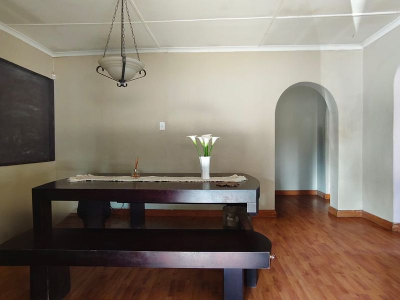 A dining room featuring laminate flooring, an arched doorway, and a classic pendant light fixture, offering a neutral canvas for interior updates.