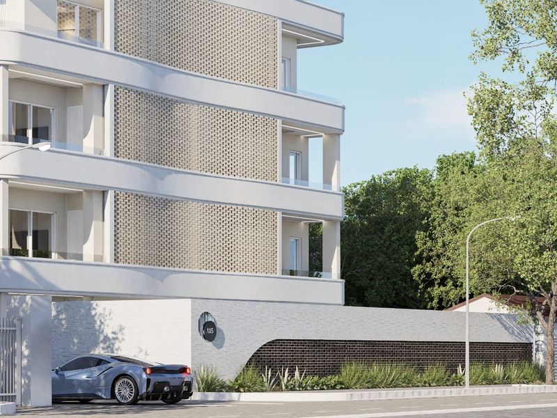 Modern apartment building exterior featuring a contemporary brick facade, glass-fronted balconies, and a secure gated entrance.
