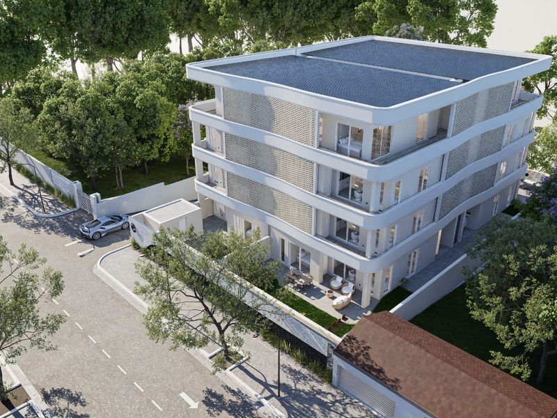 An aerial view of a modern multi-story apartment building featuring contemporary architecture, private balconies, and secure perimeter fencing.