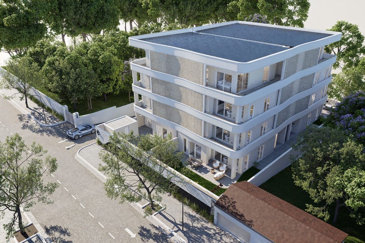 An aerial view of a modern multi-story apartment building featuring contemporary architecture, private balconies, and secure perimeter fencing.