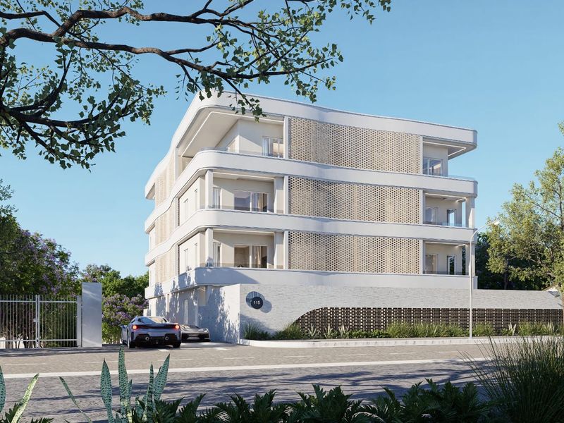A modern apartment building exterior featuring curved balconies, decorative brickwork, and a secure gated entrance.