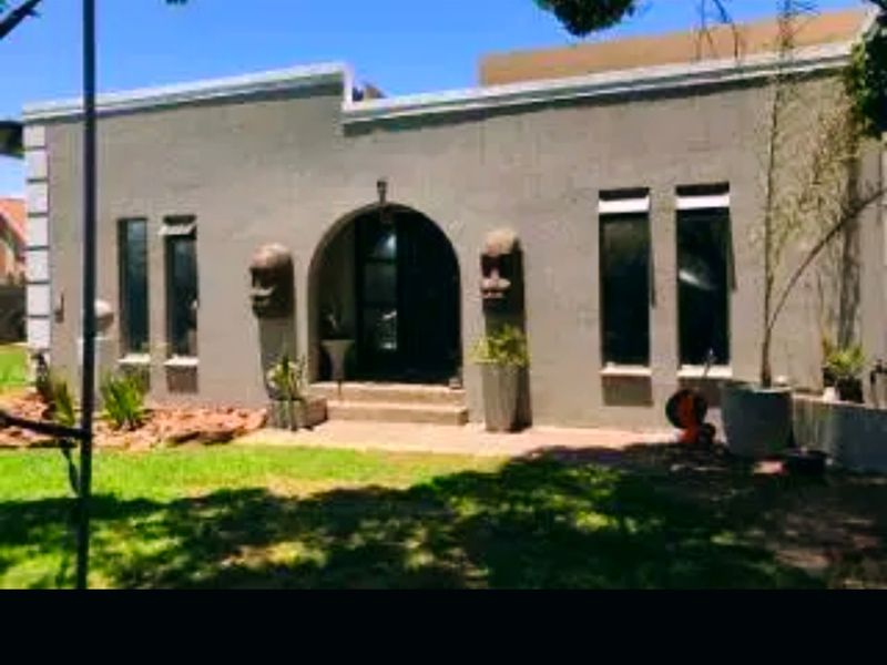Front elevation of a single-story house featuring a distinctive arched entrance and a neutral concrete facade.