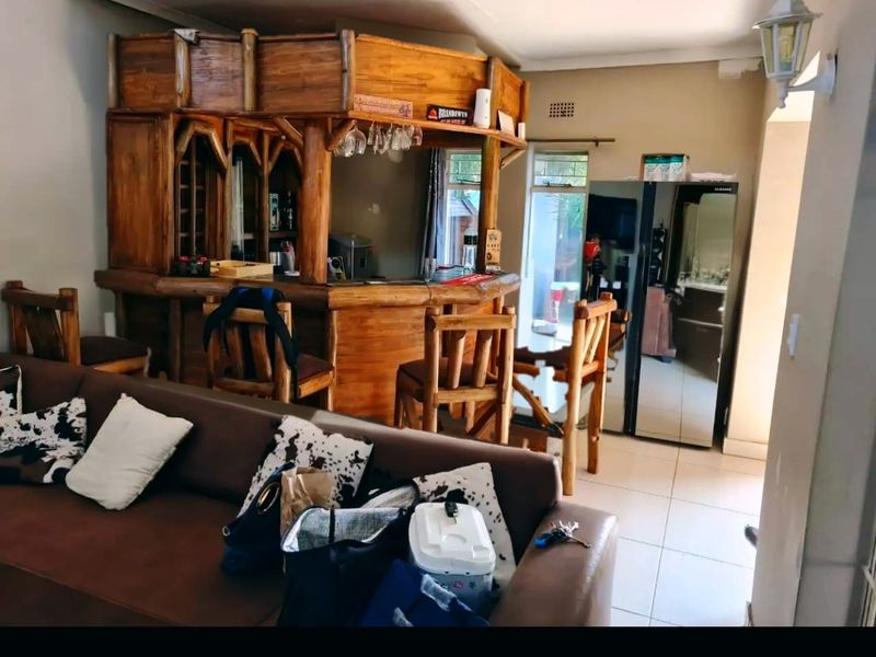 A dedicated bar area featuring a built-in wooden counter and tiled flooring, providing a functional space for entertainment.
