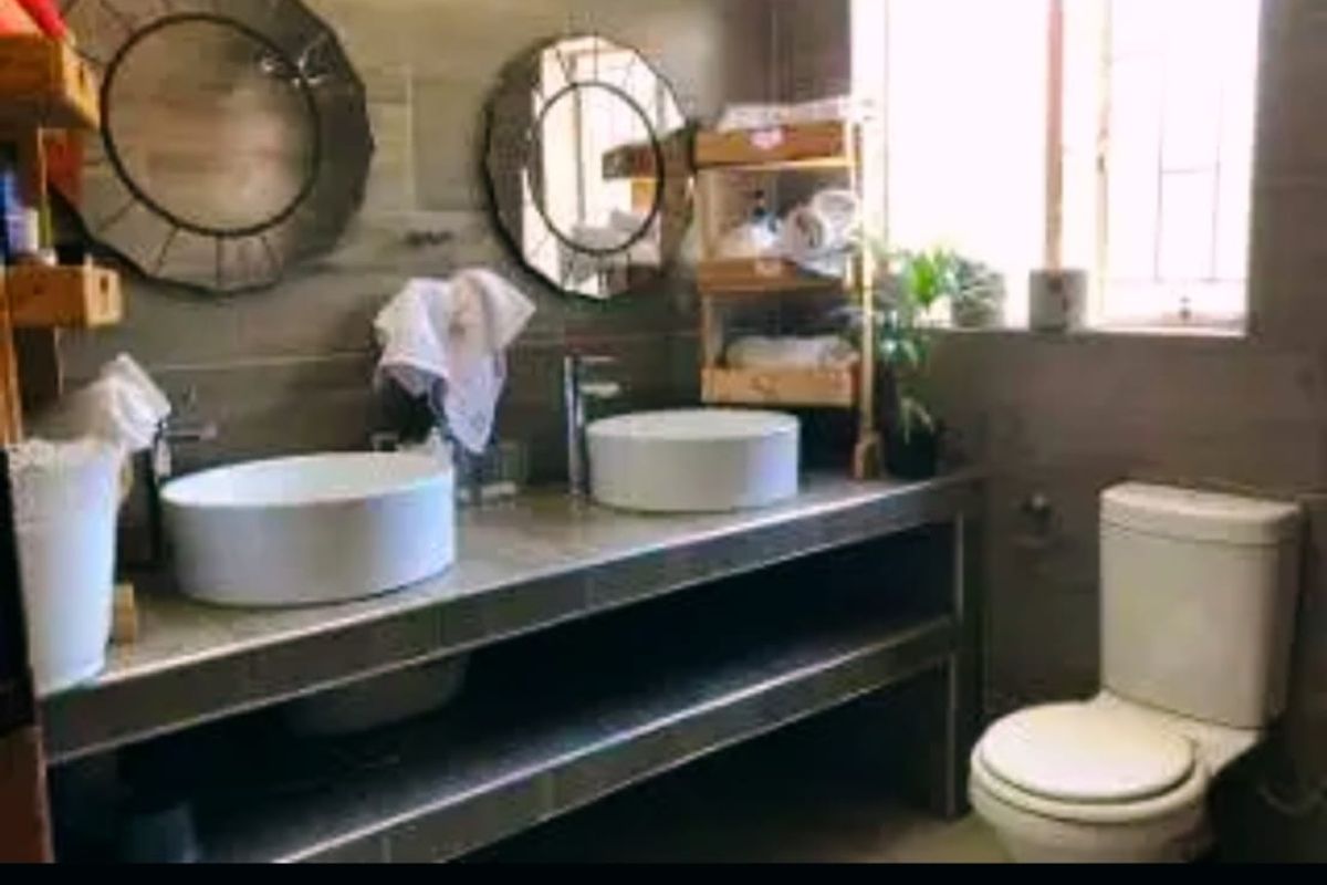 A functional bathroom featuring a double vanity with vessel sinks, chrome fixtures, and tiled wall finishes, providing a practical and modern layout.