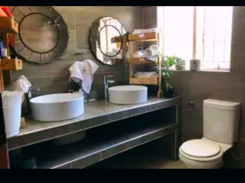 A functional bathroom featuring a double vanity with vessel sinks, chrome fixtures, and tiled wall finishes, providing a practical and modern layout.