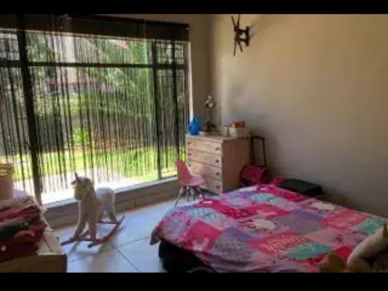 A bedroom featuring large windows that provide natural light and tiled flooring throughout.